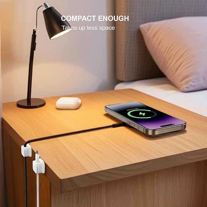 Smartphone charging on a nightstand with a lamp and white pillow in the background